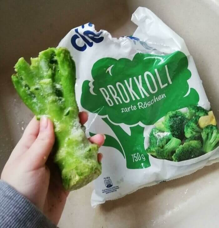 A hand holding a bag of broccoli Description automatically generated with medium confidence